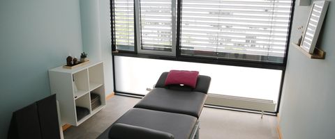 Behandlungsraum mit Liege und hellblauer Wand